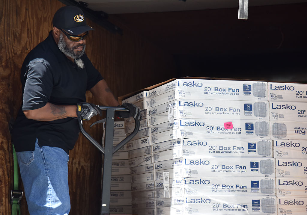 John Turner maneuvers a pallet jack holding donated boxed fans